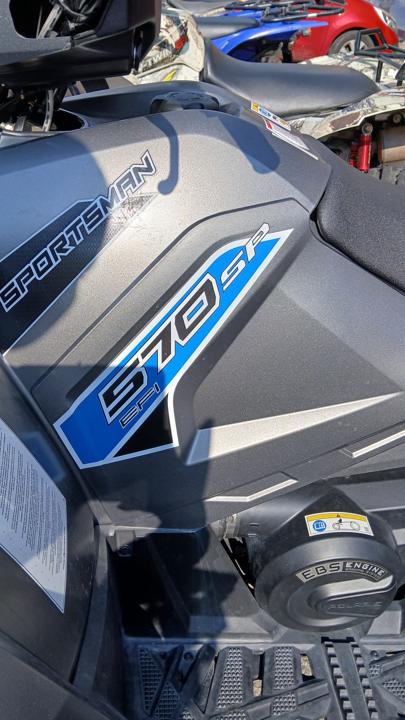 Polaris Sportsman 570 ATV, carrozzeria grigia testurizzata con decalcomanie blu e bianche.