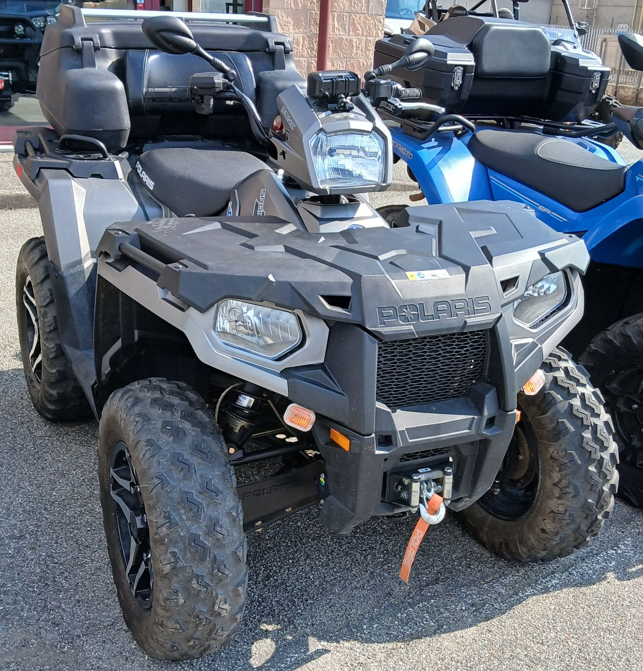 ATV Polaris grigio e nero con cassone di carico parcheggiato all'aperto.