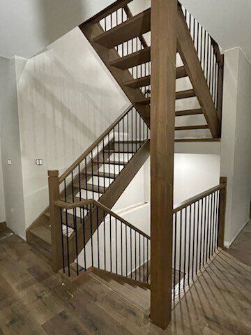 Wooden staircase with dark railing and brown treads.