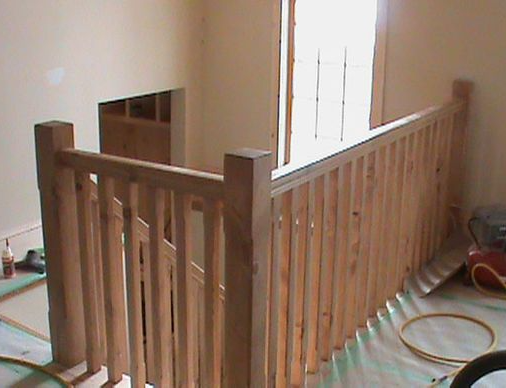 Wooden staircase with railing inside a house, viewed from the top.