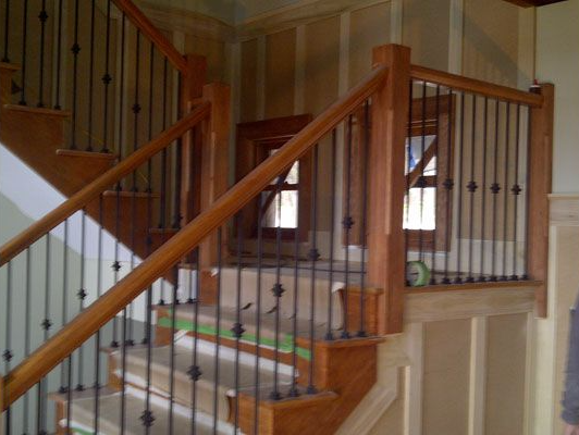 Wooden staircase with dark metal balusters, leading upwards.