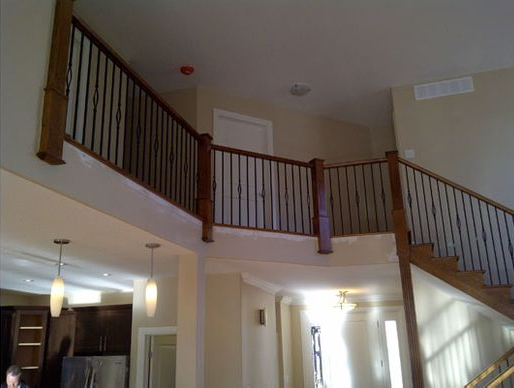Interior view of a house with a wooden staircase and railing, high ceilings, and natural light.