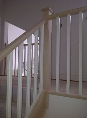 Staircase with white balusters and wooden handrail in a well-lit interior.