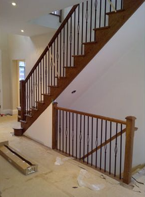 Wooden staircase with black iron balusters in a home.