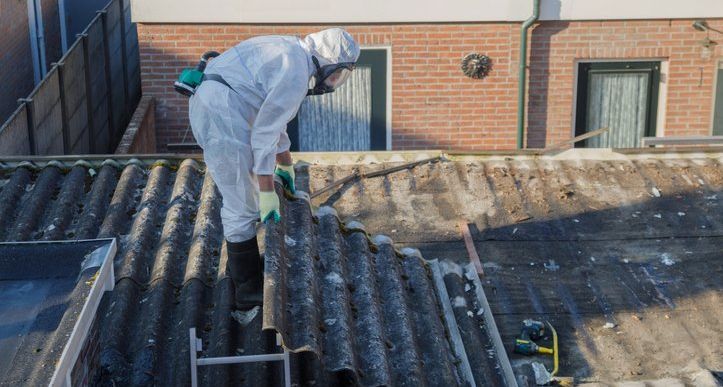Kampen, The Netherlands, april 29th, 2019: Men in protective suits are removing asbestos cement corrugated roofing