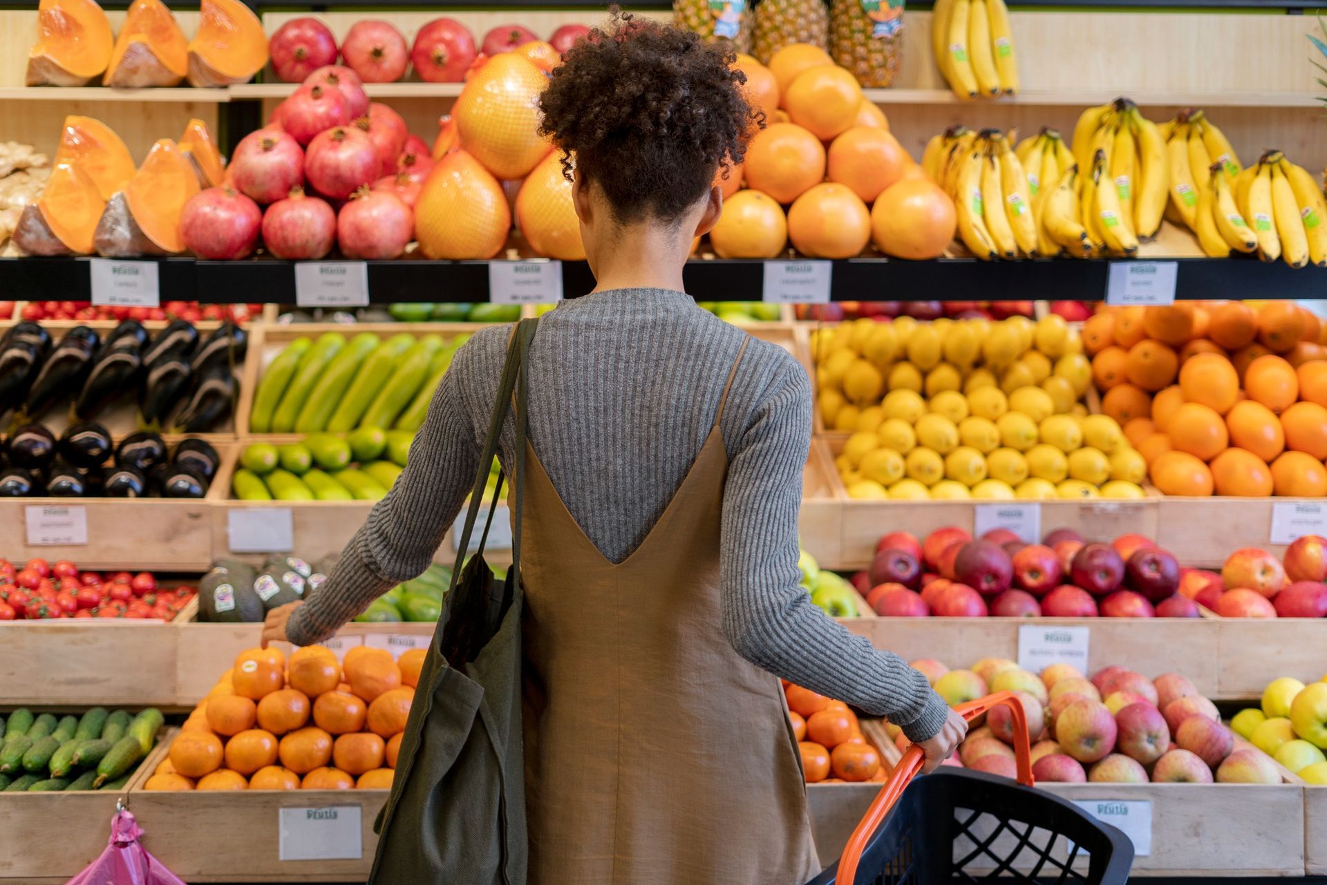 A woman is looking at fruits and vegetables in a grocery store.