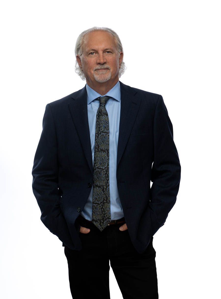 A man in a suit and tie is standing in front of a window.