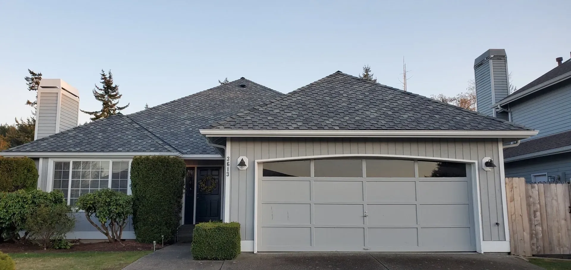 A house with a gray roof and a white garage door