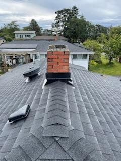 There is a chimney on the roof of a house.