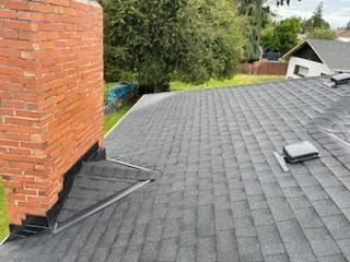 There is a brick chimney on the roof of a house.