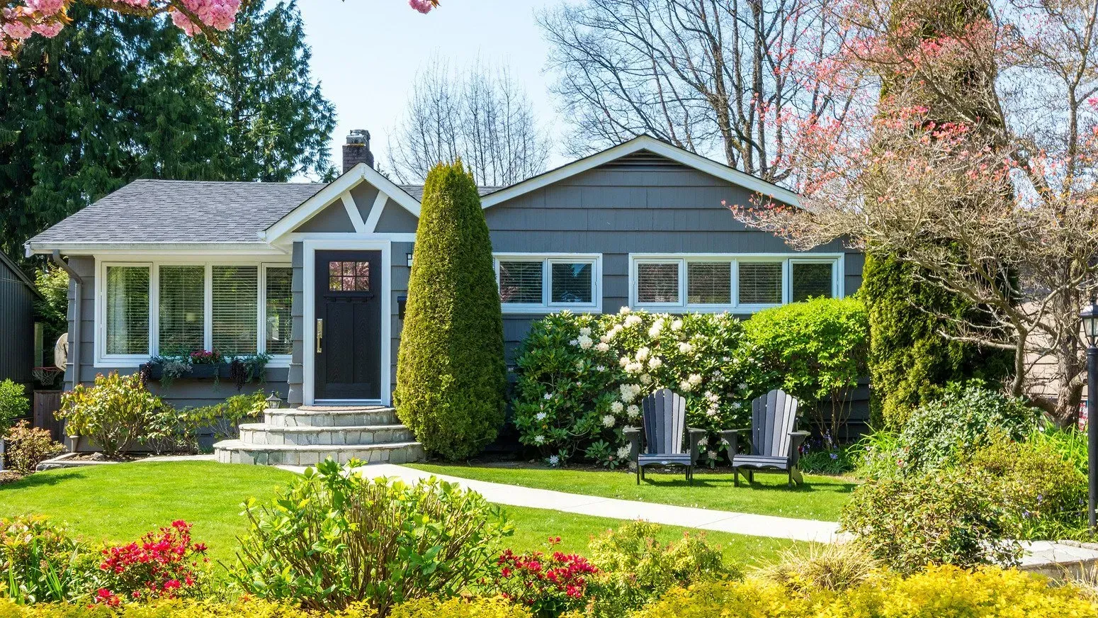 A house with a lush green lawn and flowers in front of it.