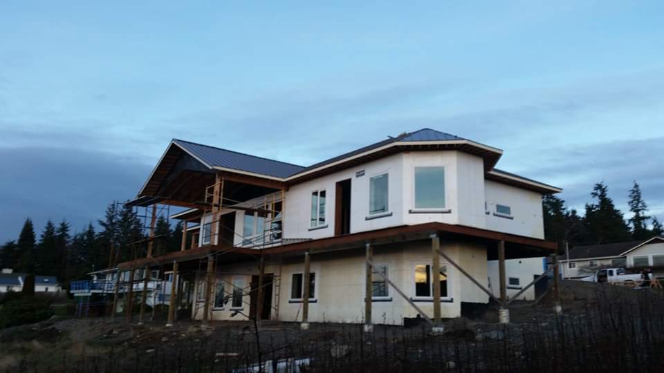 A large white house is being built on top of a hill.