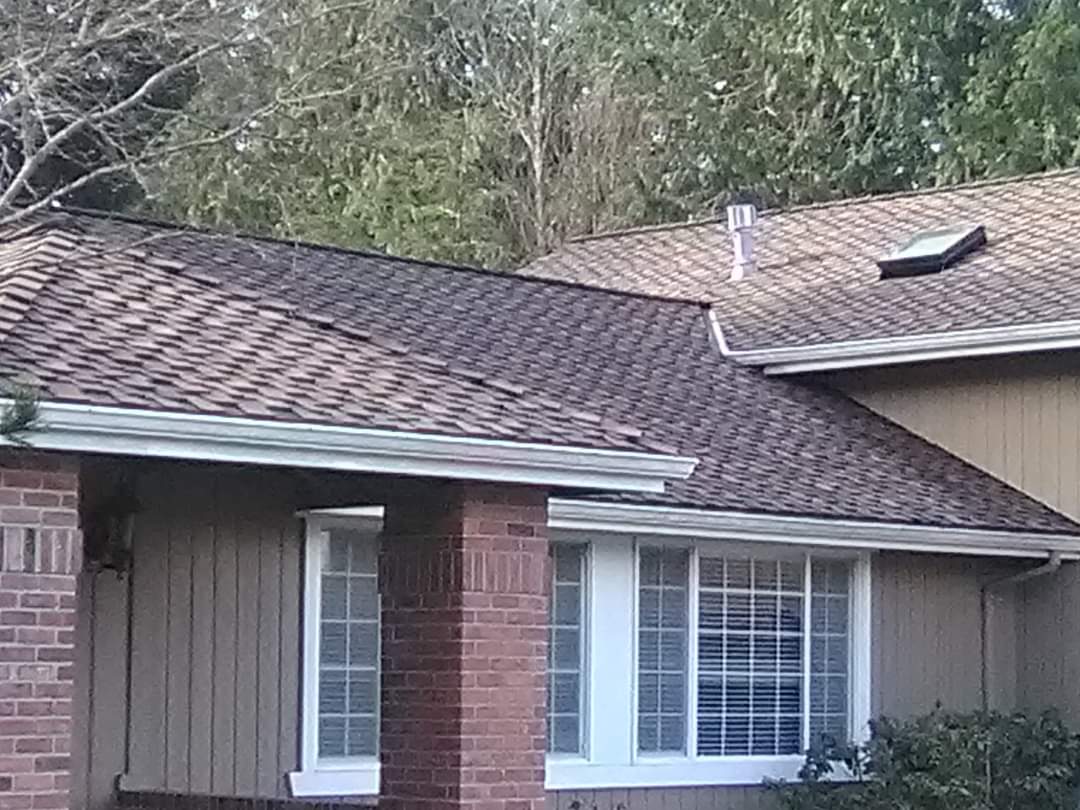 A brick house with a brown roof and a skylight on the roof.
