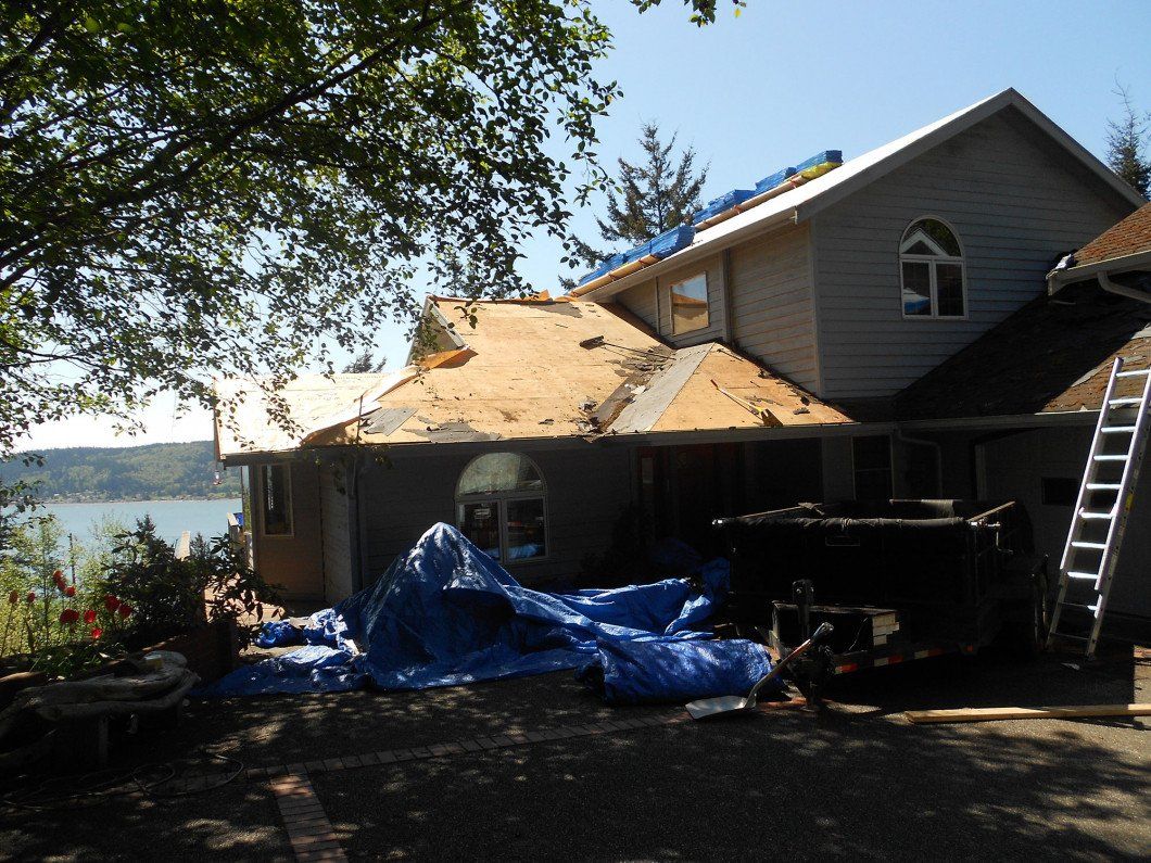 A house with a blue tarp on the ground in front of it