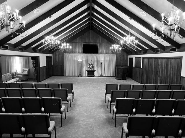Interior of a funeral home with rows of chairs, a draped altar, and chandeliers.