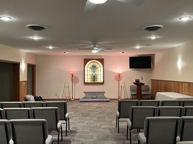Interior view of a chapel with seating, stained glass window, and a podium.