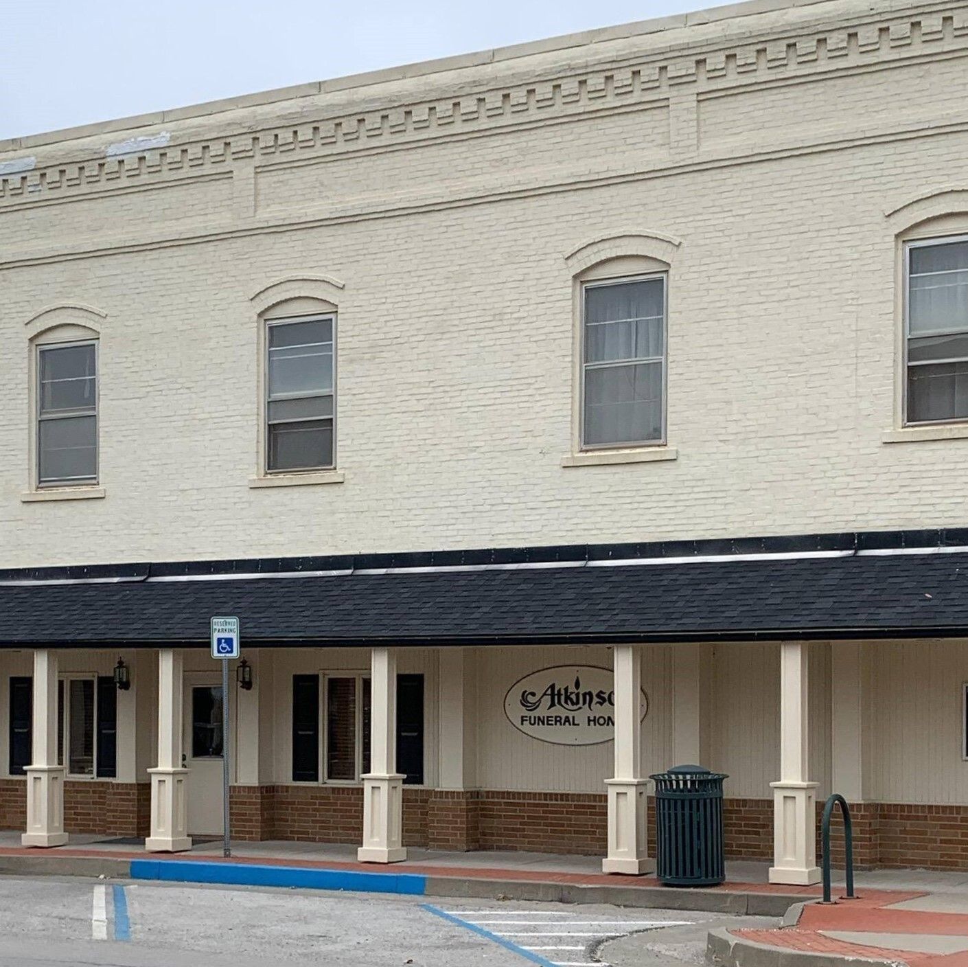 Cream-colored brick building with arched windows. Black awning over ground level. Sign says 