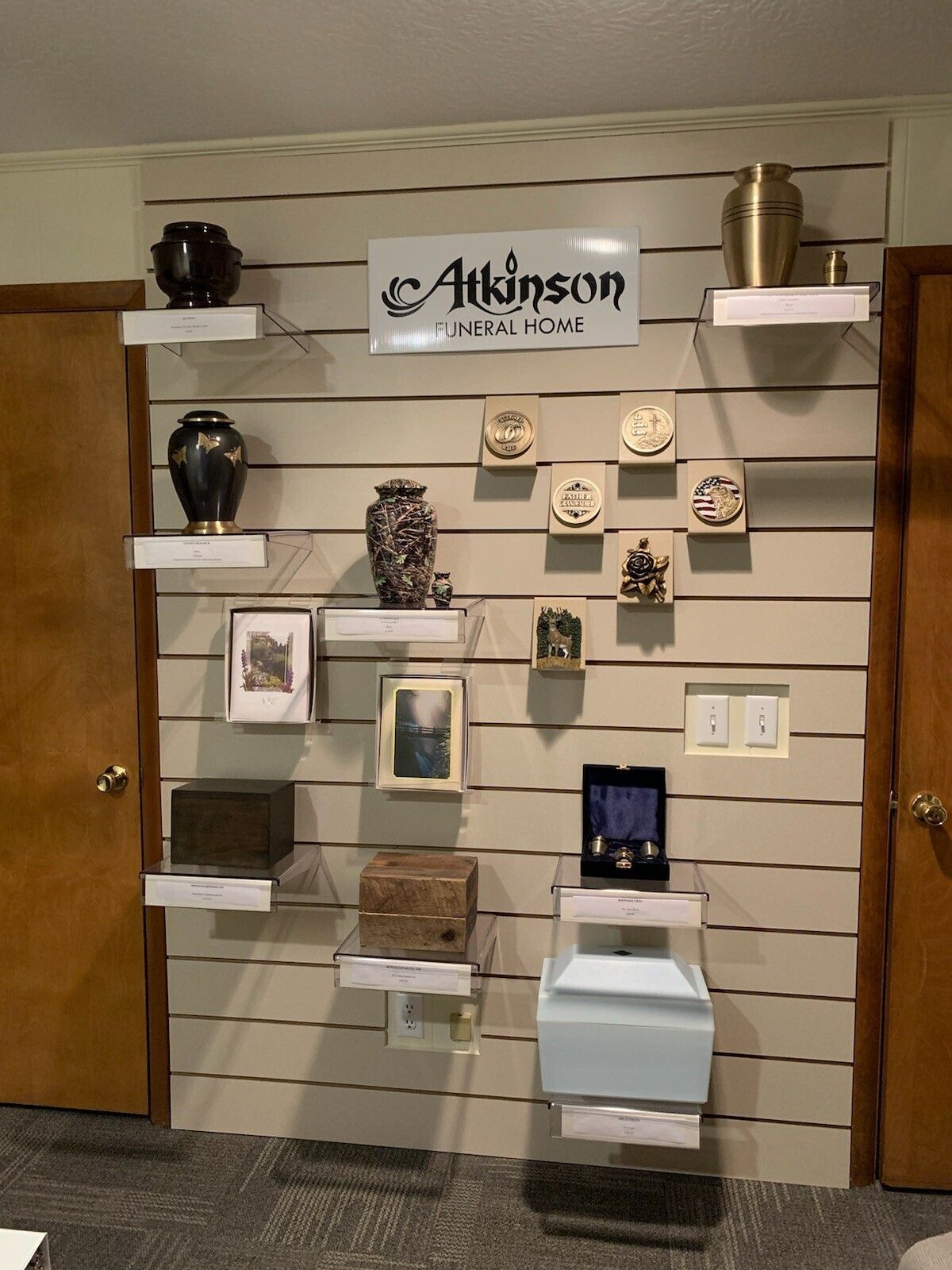 Display of memorial urns and keepsakes on a wall with the 