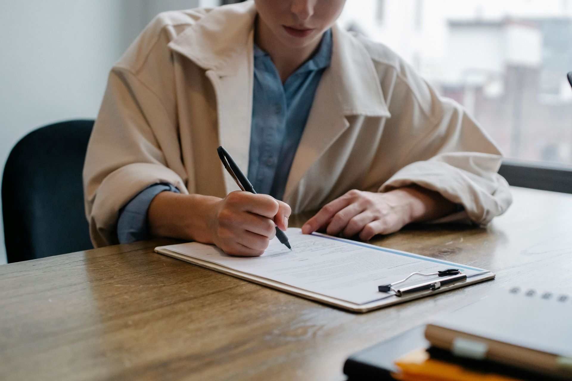 A woman signing a paper on a desk.