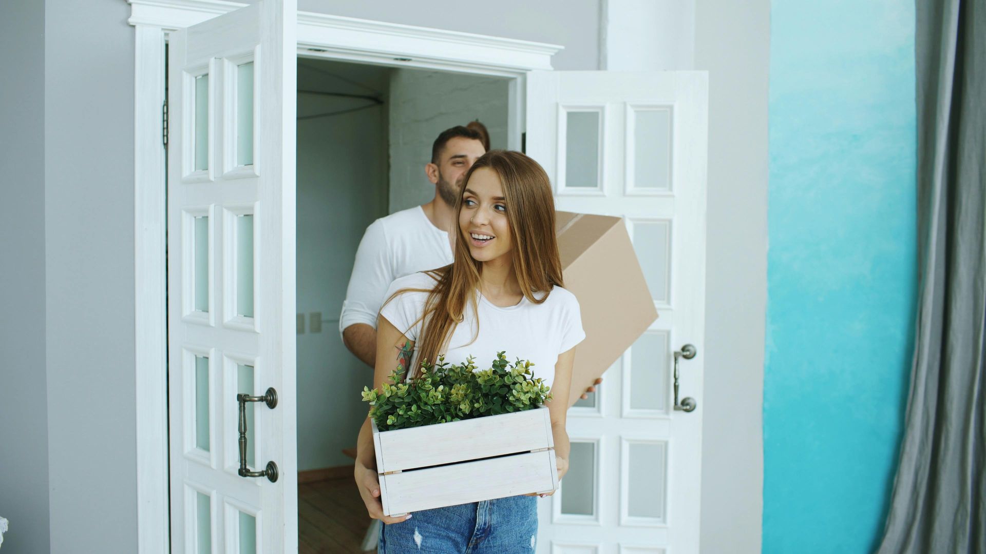 Delivery person carrying a potted plant into a bright home doorway