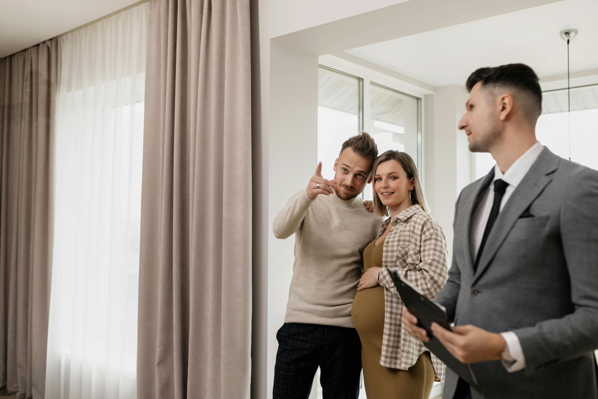 Real estate agent showing a bright apartment to two smiling clients