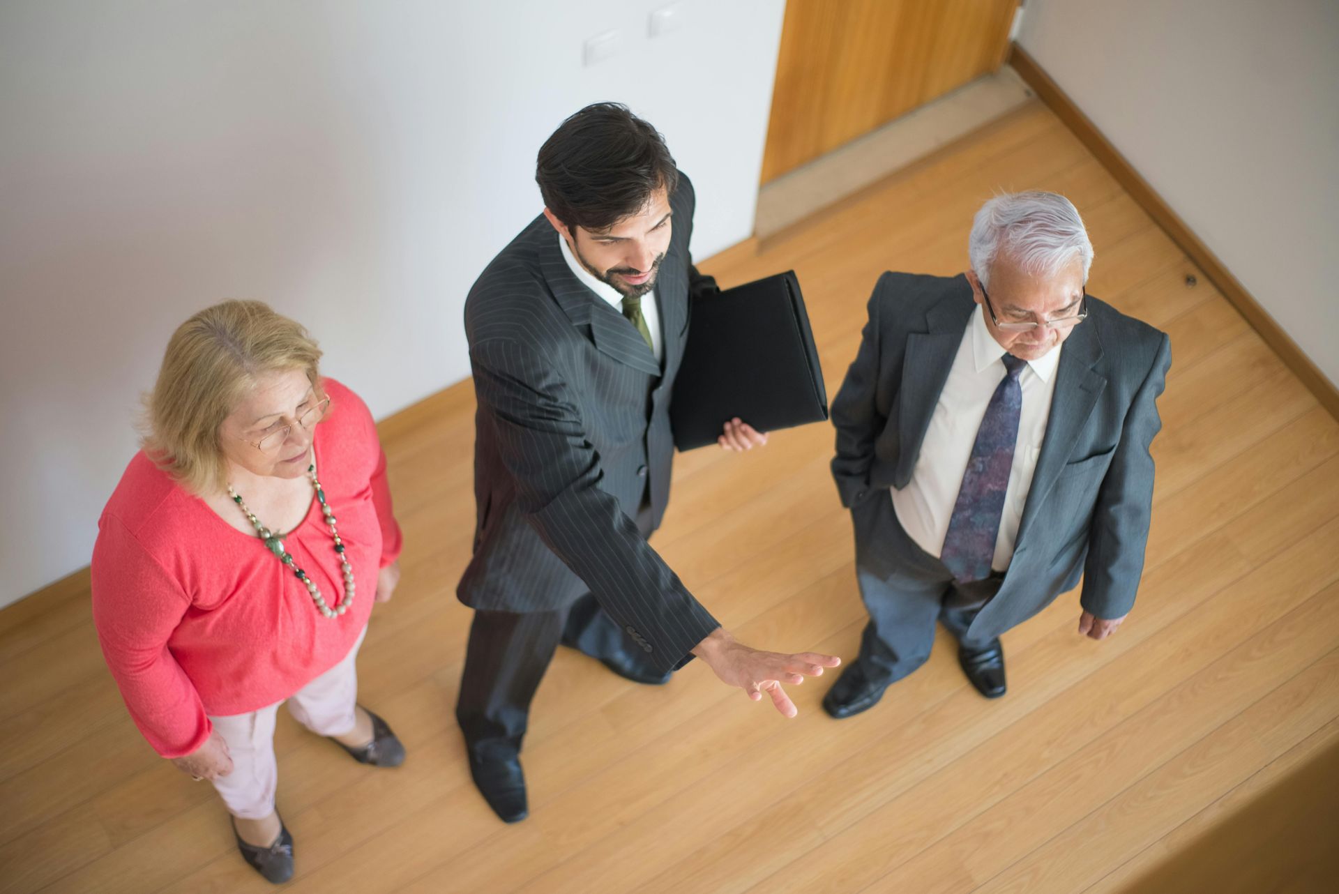 Three business people in a hallway, one gesturing while the others listen.