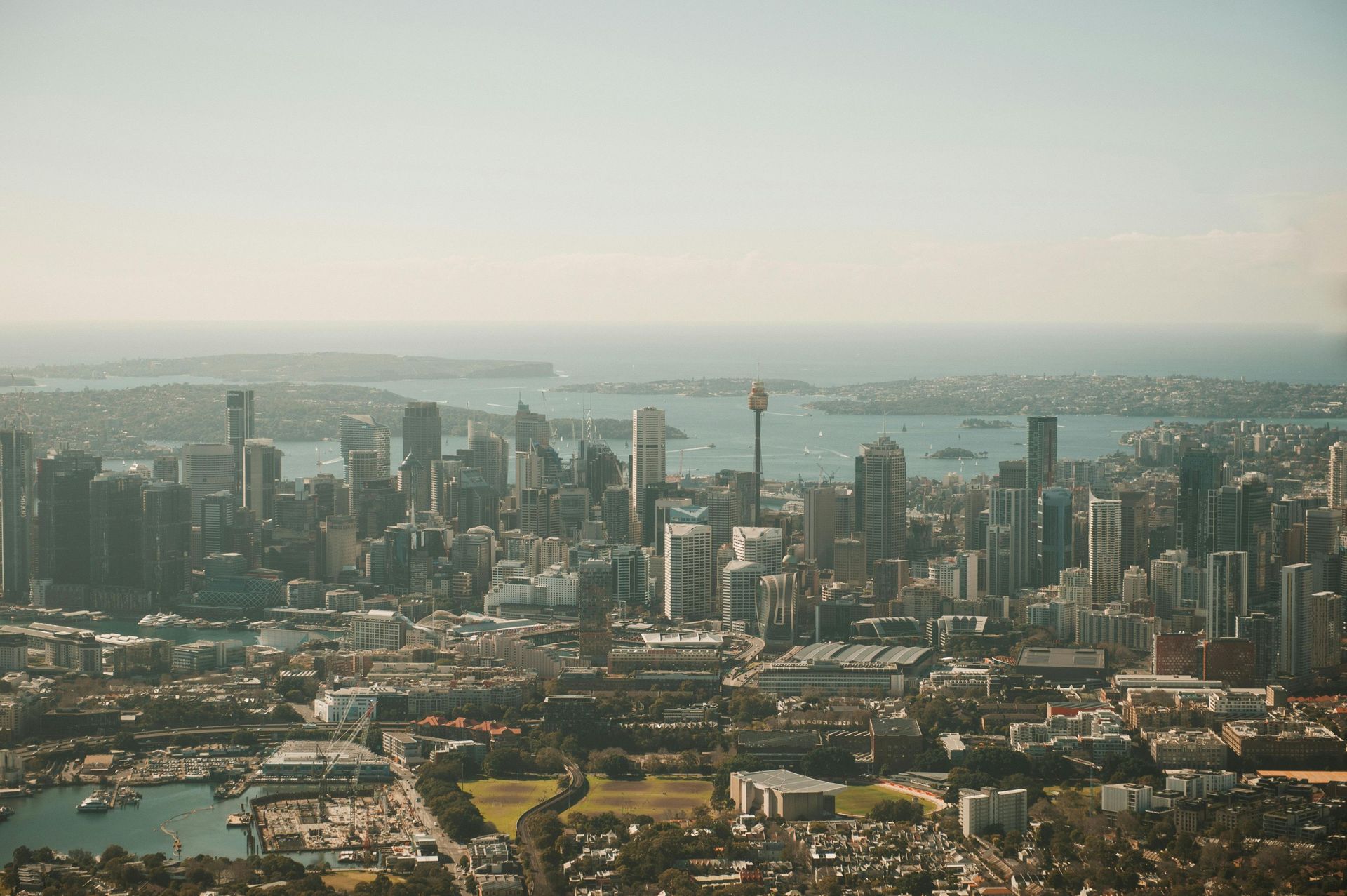 City skyline with tall buildings beside a waterfront under a hazy sky
