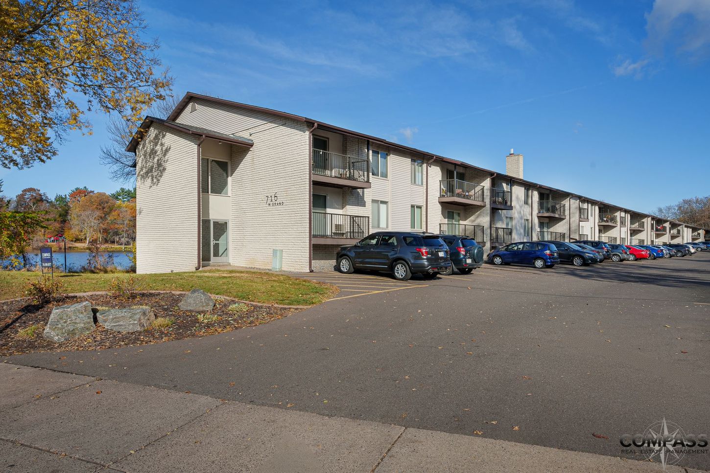 Apartment complex parking lot with parked cars and autumn trees