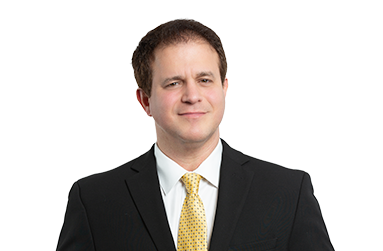 Attorney Ernesto Gonzalez in a suit and tie is standing in front of a white background. 