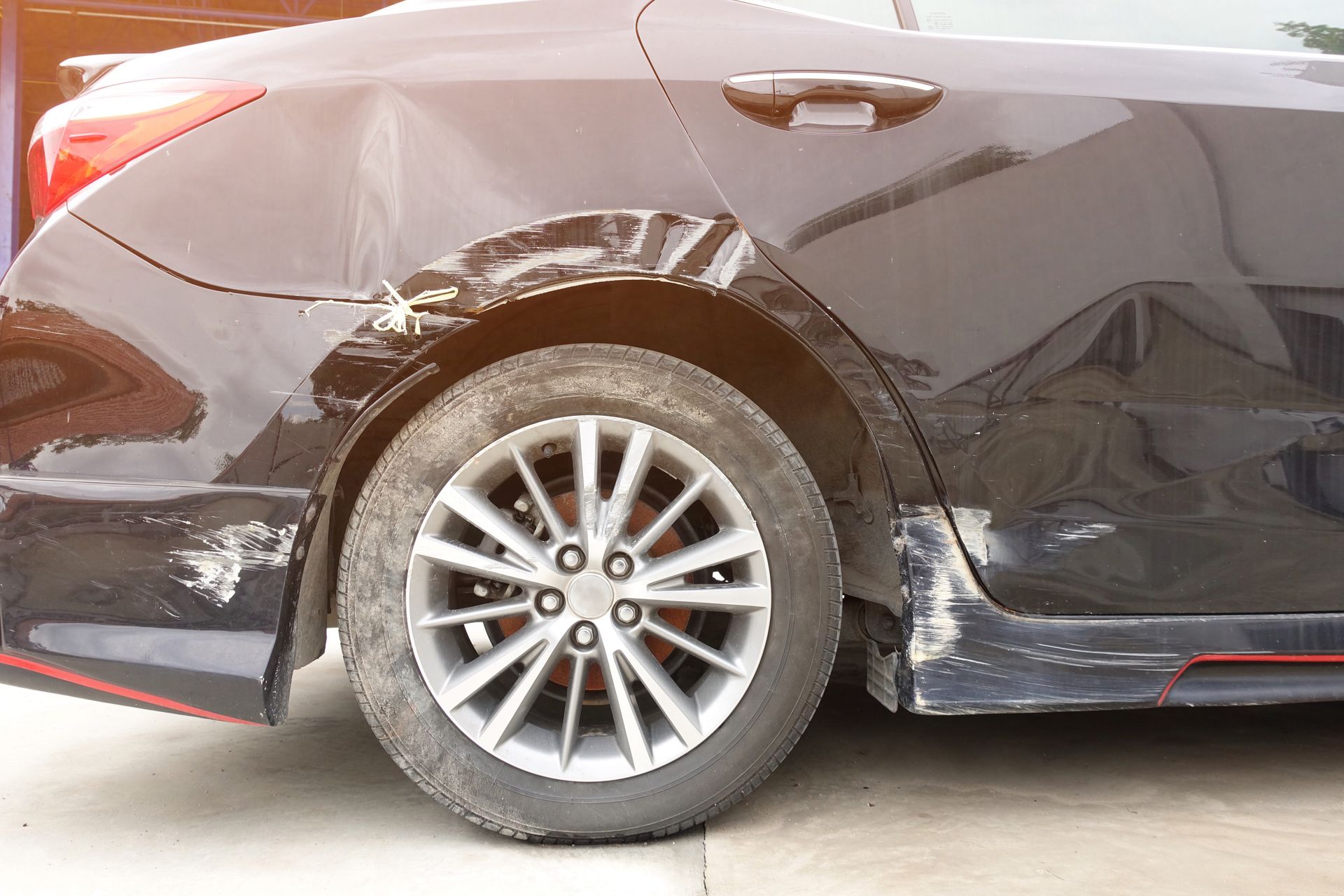 a black car with a damaged fender is parked after a side swipe car accident.  Attorney Ernesto Gonzalez Article on types of accidents and how to avoid them.