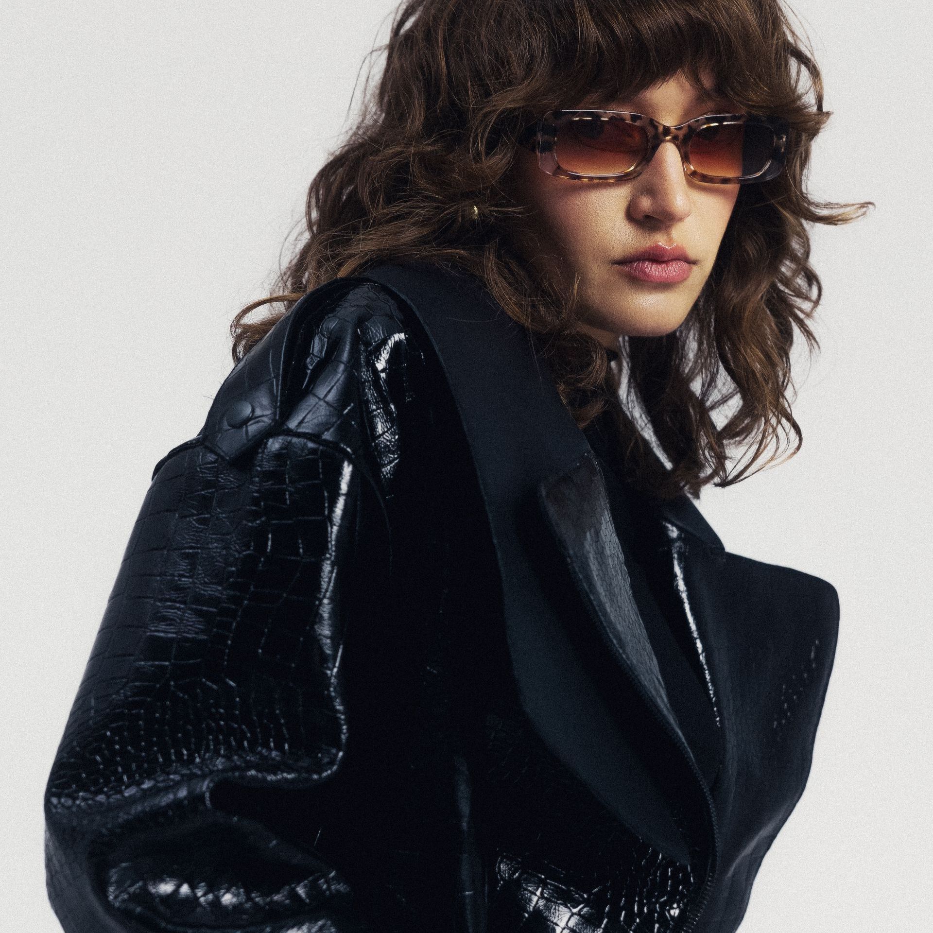 Kobieta w okularach przeciwsłonecznych i czarnej kurtce