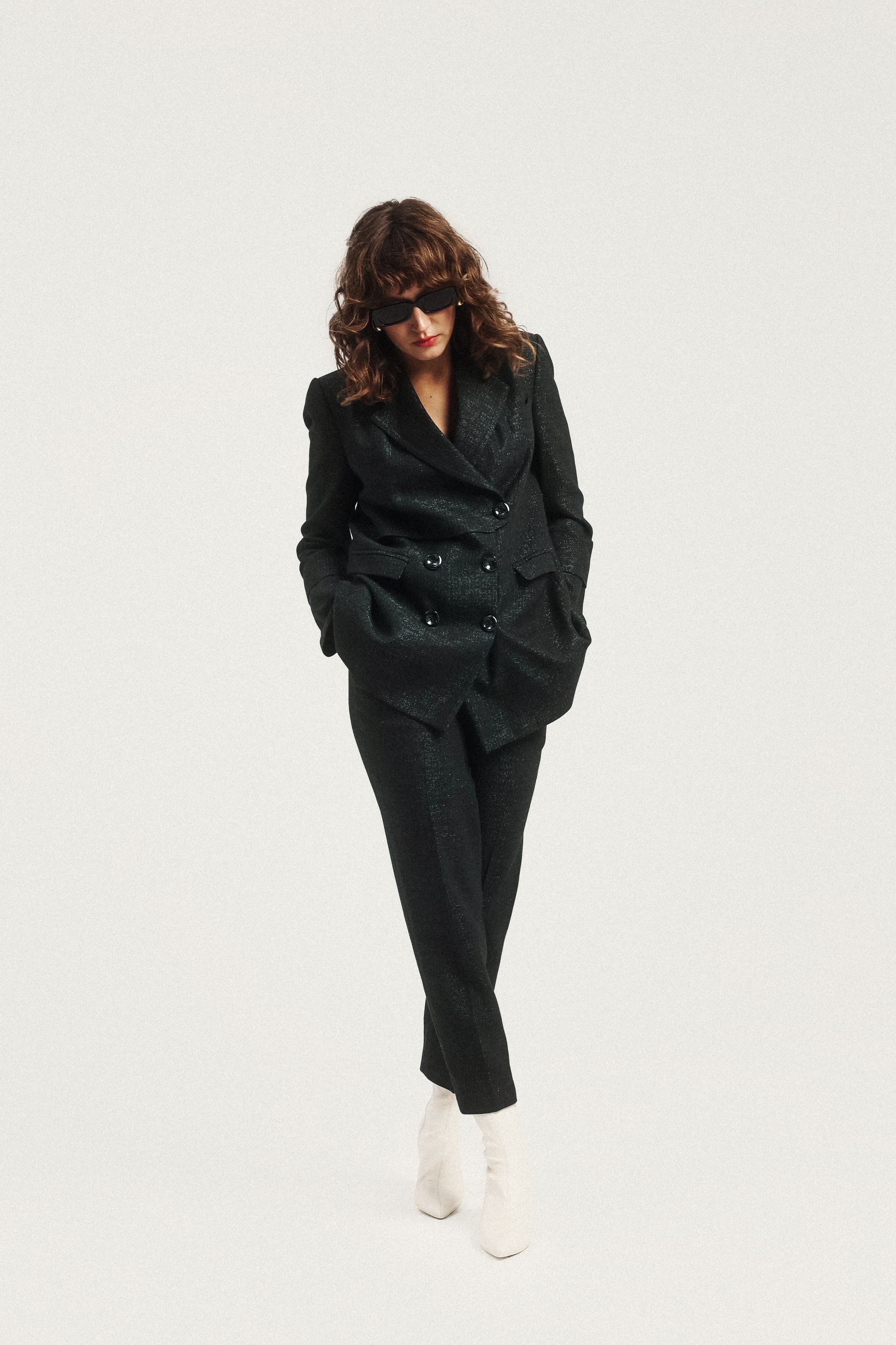 Kobieta ma na sobie czarny garnitur i białe buty