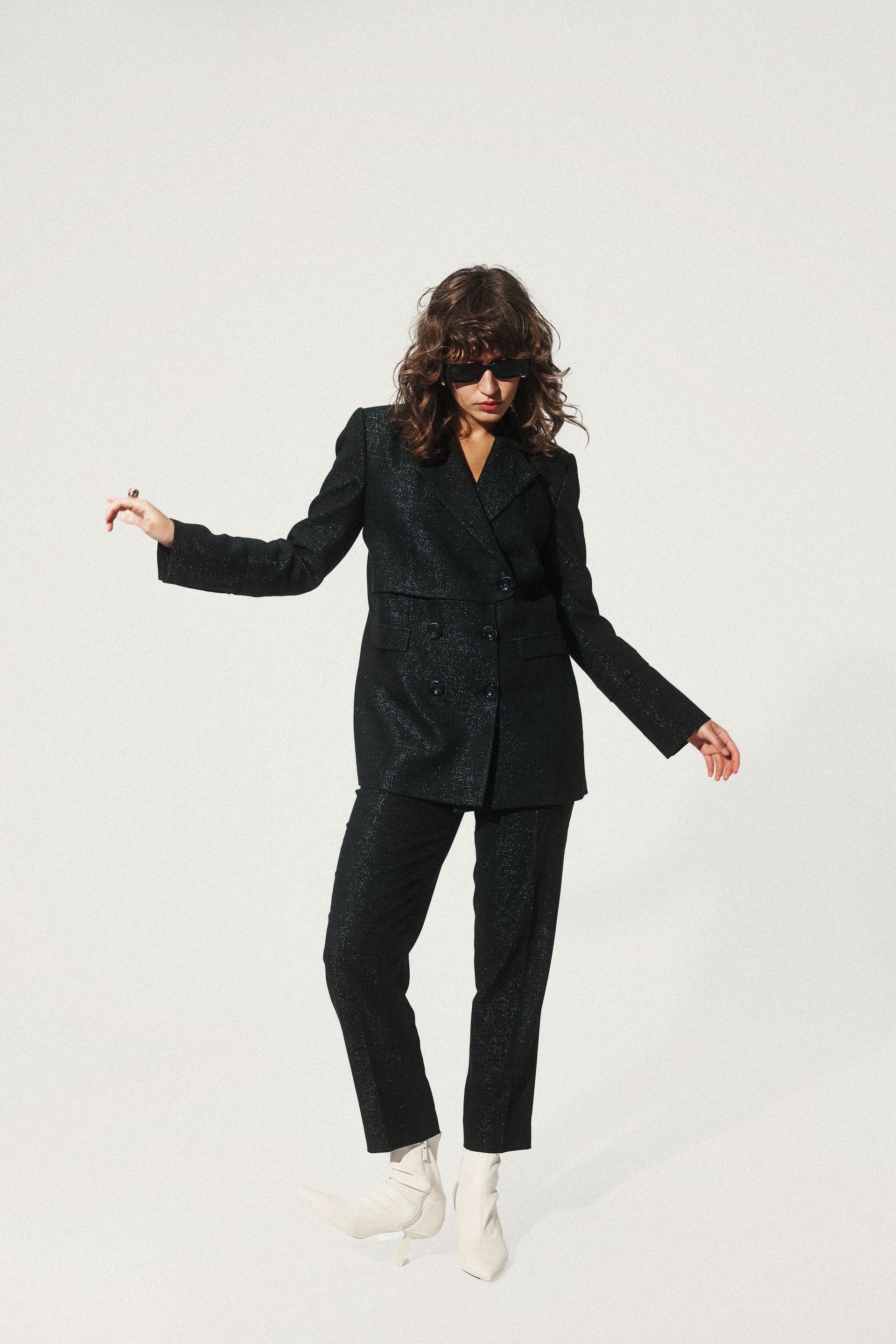 Kobieta w czarnym garniturze i białych butach tańczy