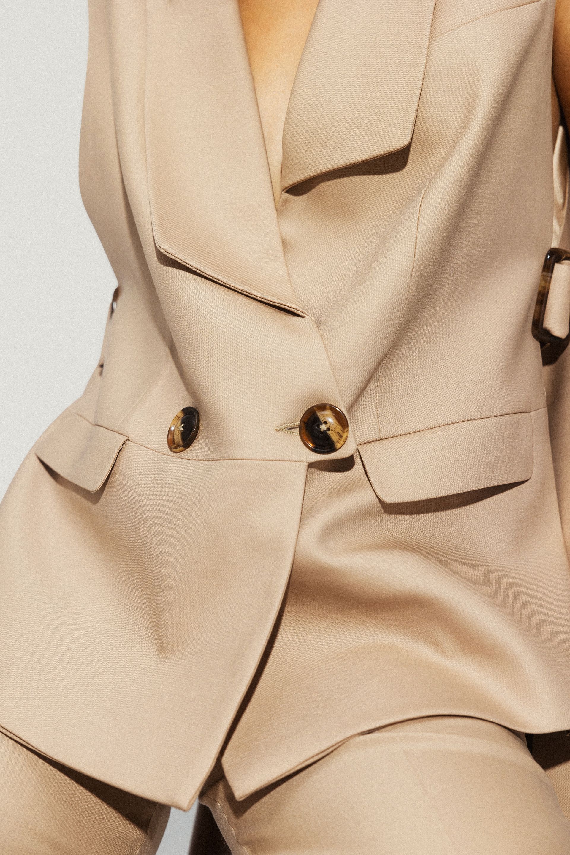 Kobieta ma na sobie brązowy garnitur ze złotymi guzikami