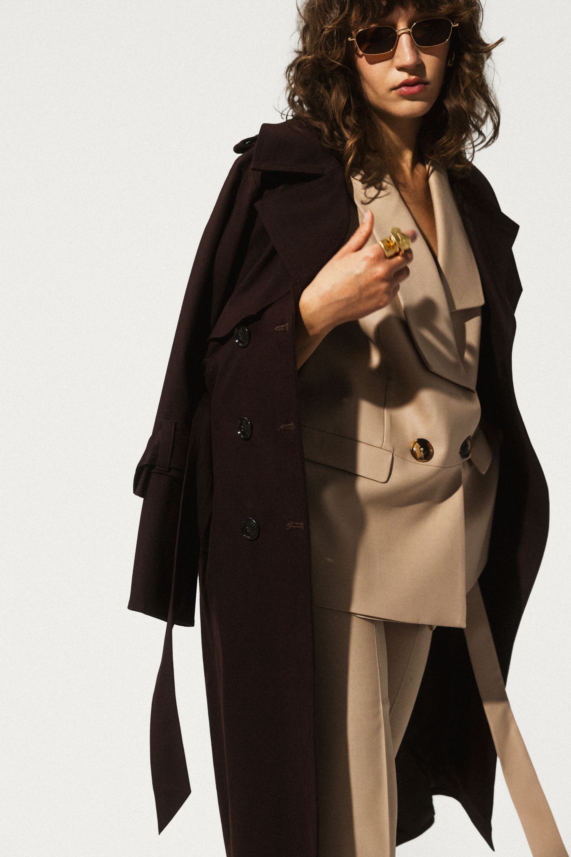 Kobieta w okularach przeciwsłonecznych i brązowym płaszczu