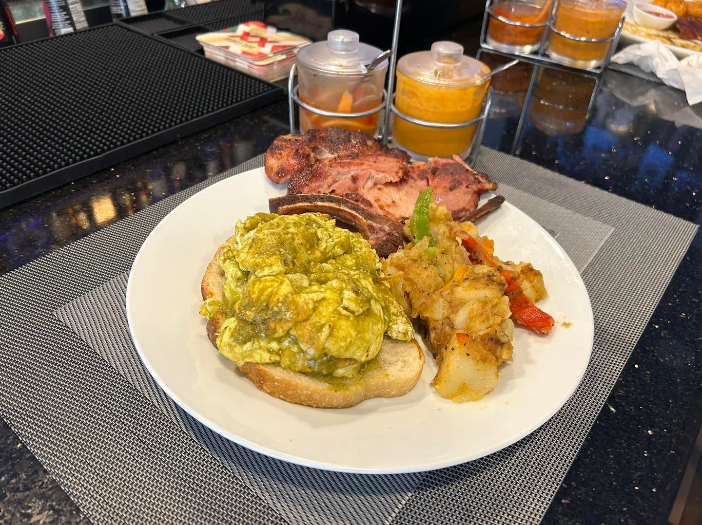 Plate of food with scrambled eggs on toast, meat, and vegetables.