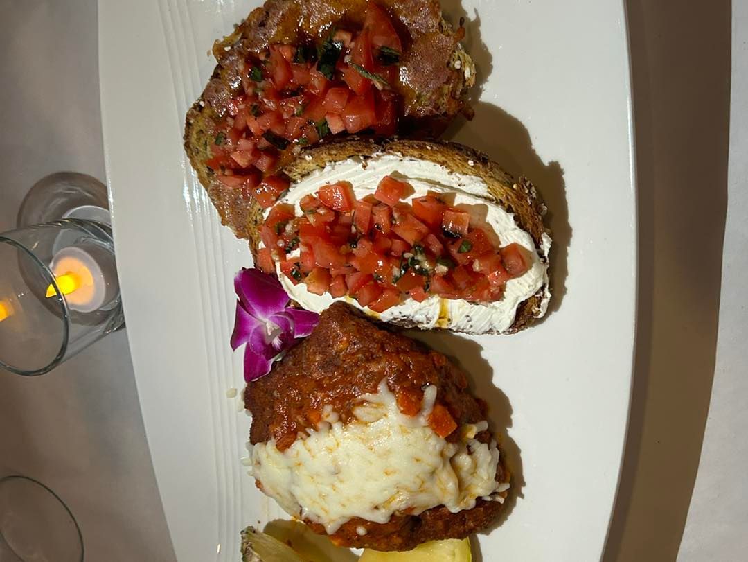 Appetizer plate with three bruschetta slices: tomato, goat cheese, and cheese.