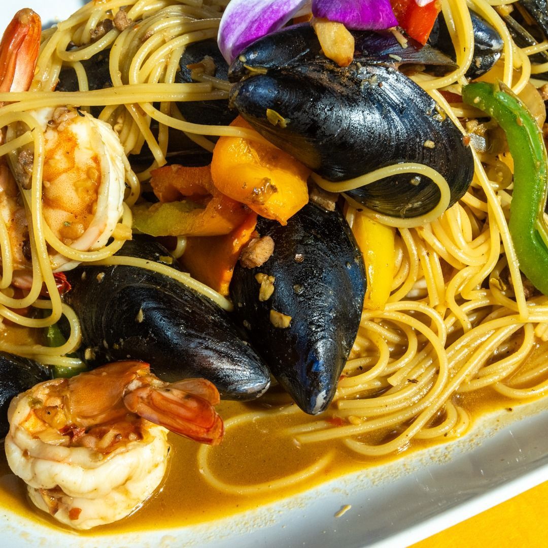 Seafood pasta dish: spaghetti with mussels, shrimp, peppers, and sauce.