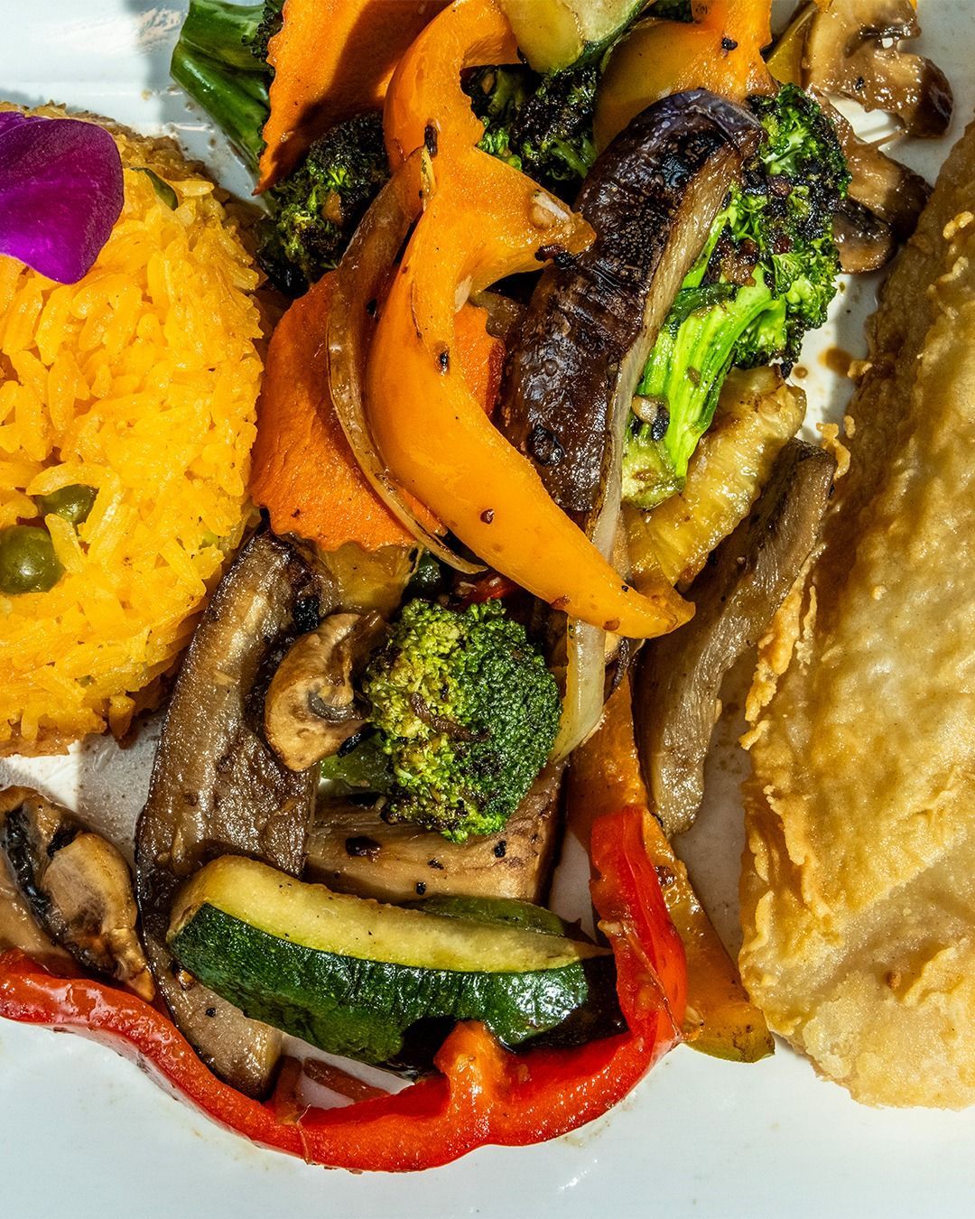 Plate of sauteed vegetables, rice, and fish fillet. Includes carrots, broccoli, zucchini, bell peppers, and mushrooms.