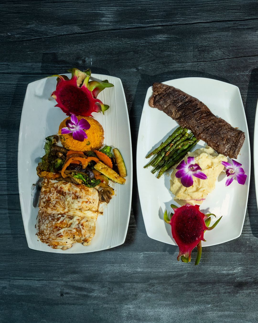 Two plates of food on a dark surface.