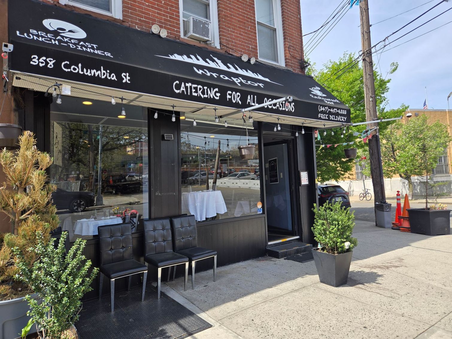 Restaurant exterior, black awning, glass windows, tables inside, chairs outside, Columbia St address.