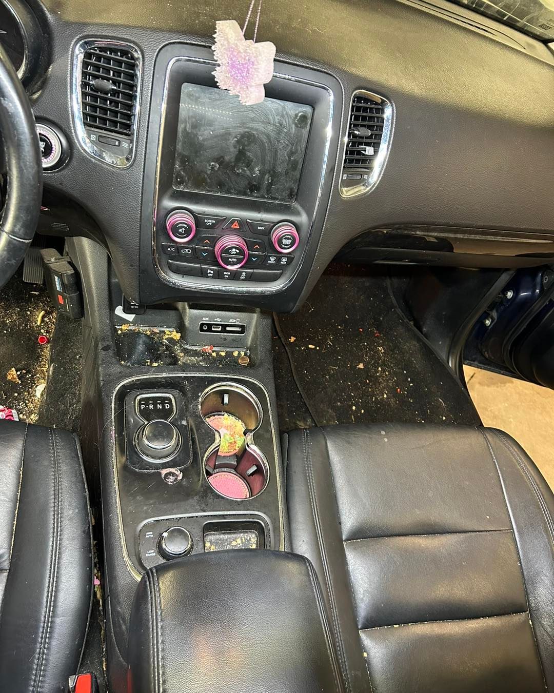 The interior of a dirty car with a butterfly hanging from the dashboard.