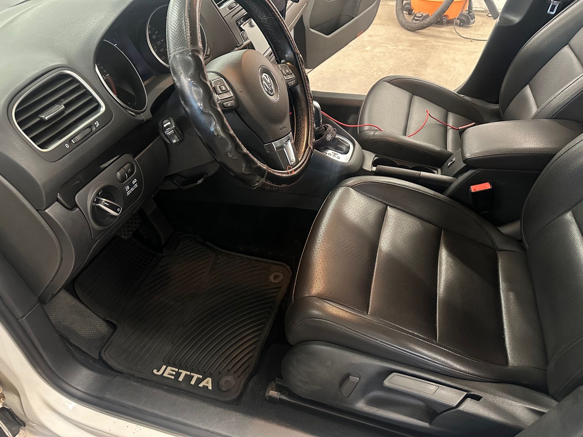 The interior of a volkswagen jetta with leather seats and a steering wheel.