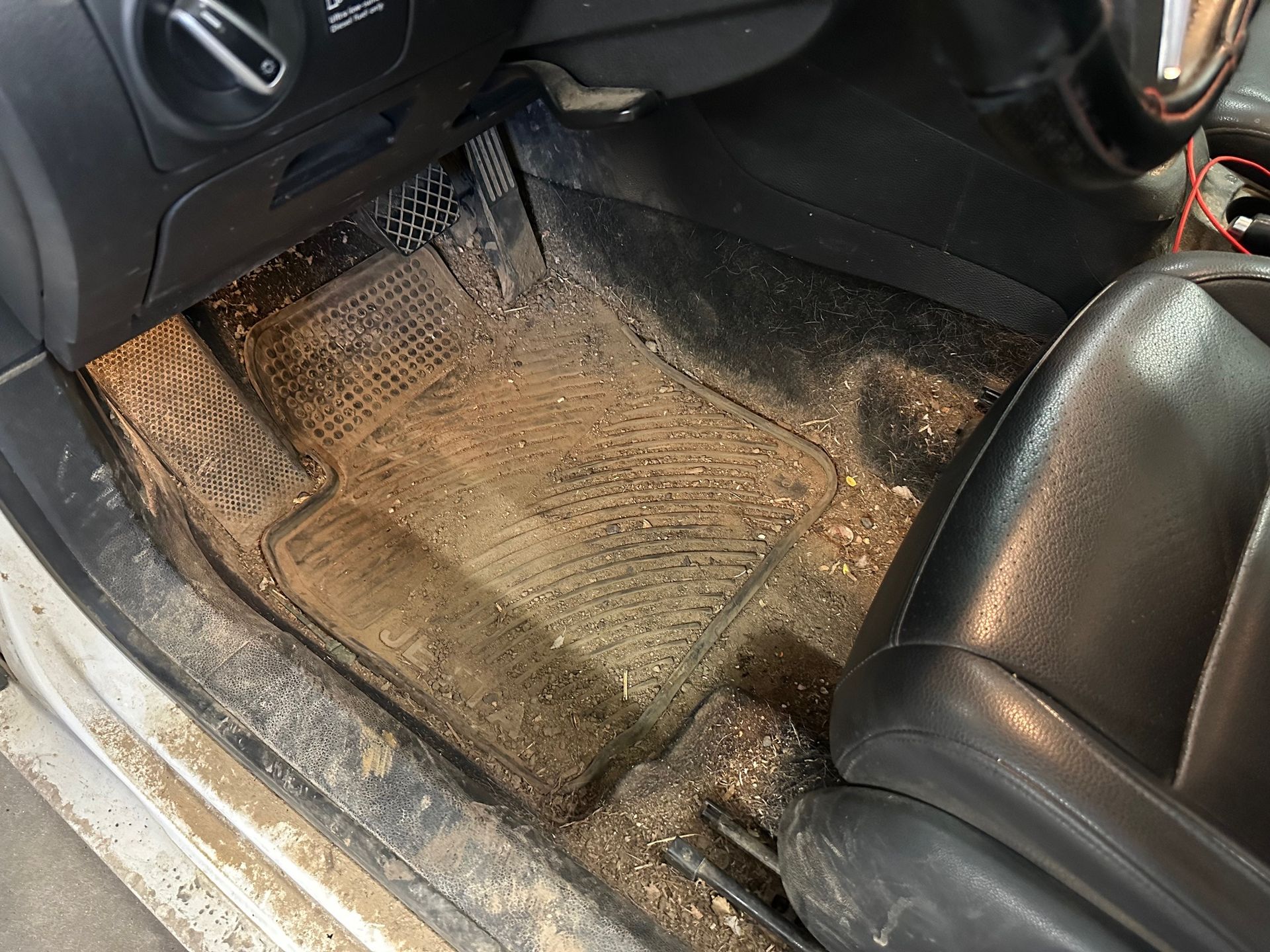 The inside of a dirty car with a dirty floor mat.