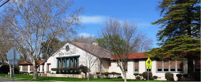 a white house with a red roof is surrounded by trees and grass .