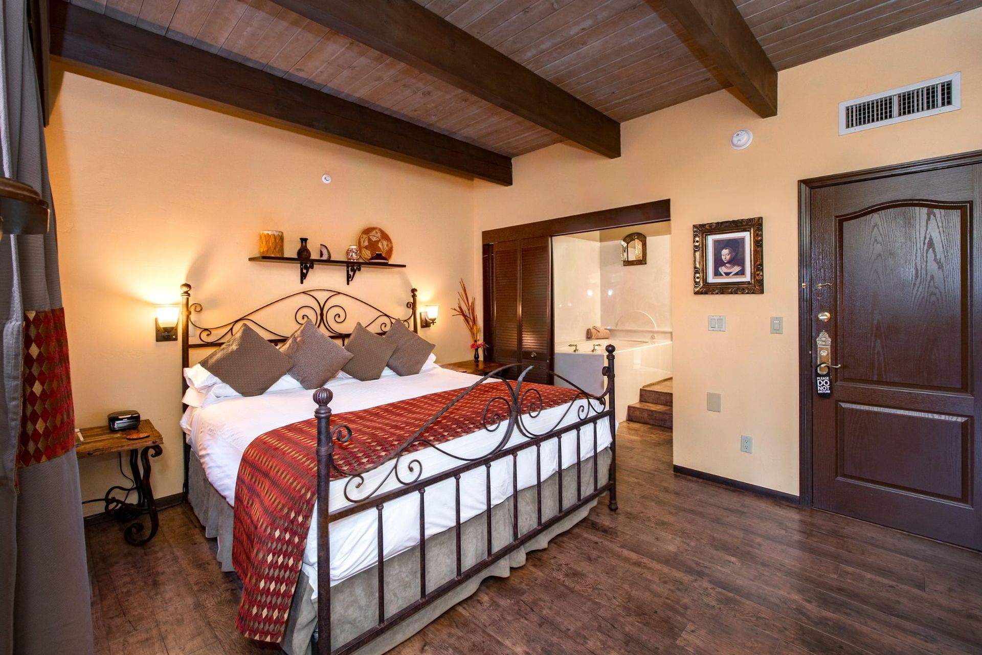 A hotel room with a king size bed and a wooden floor.