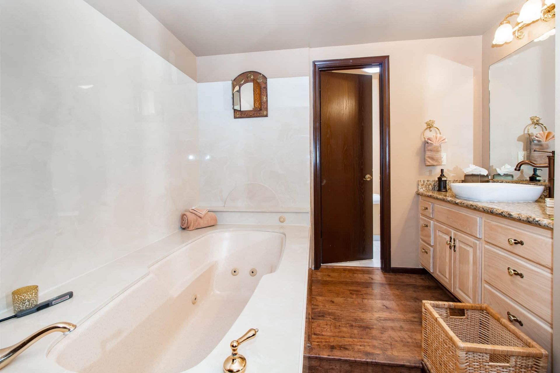 A bathroom with a jacuzzi tub , sink and mirror.