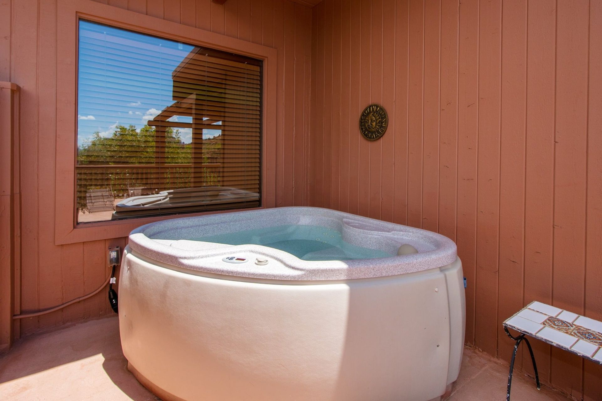 A hot tub is sitting on a patio next to a window.