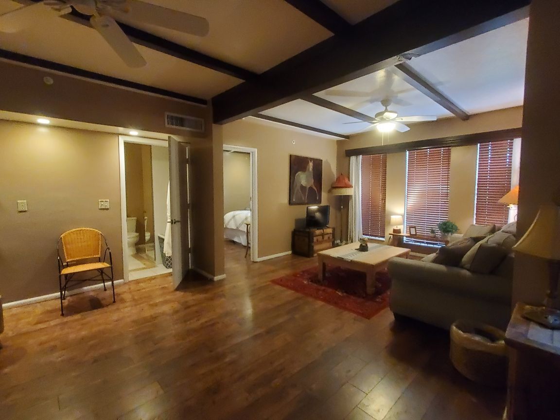 A bedroom with a king size bed , two chairs , a television and a fireplace.