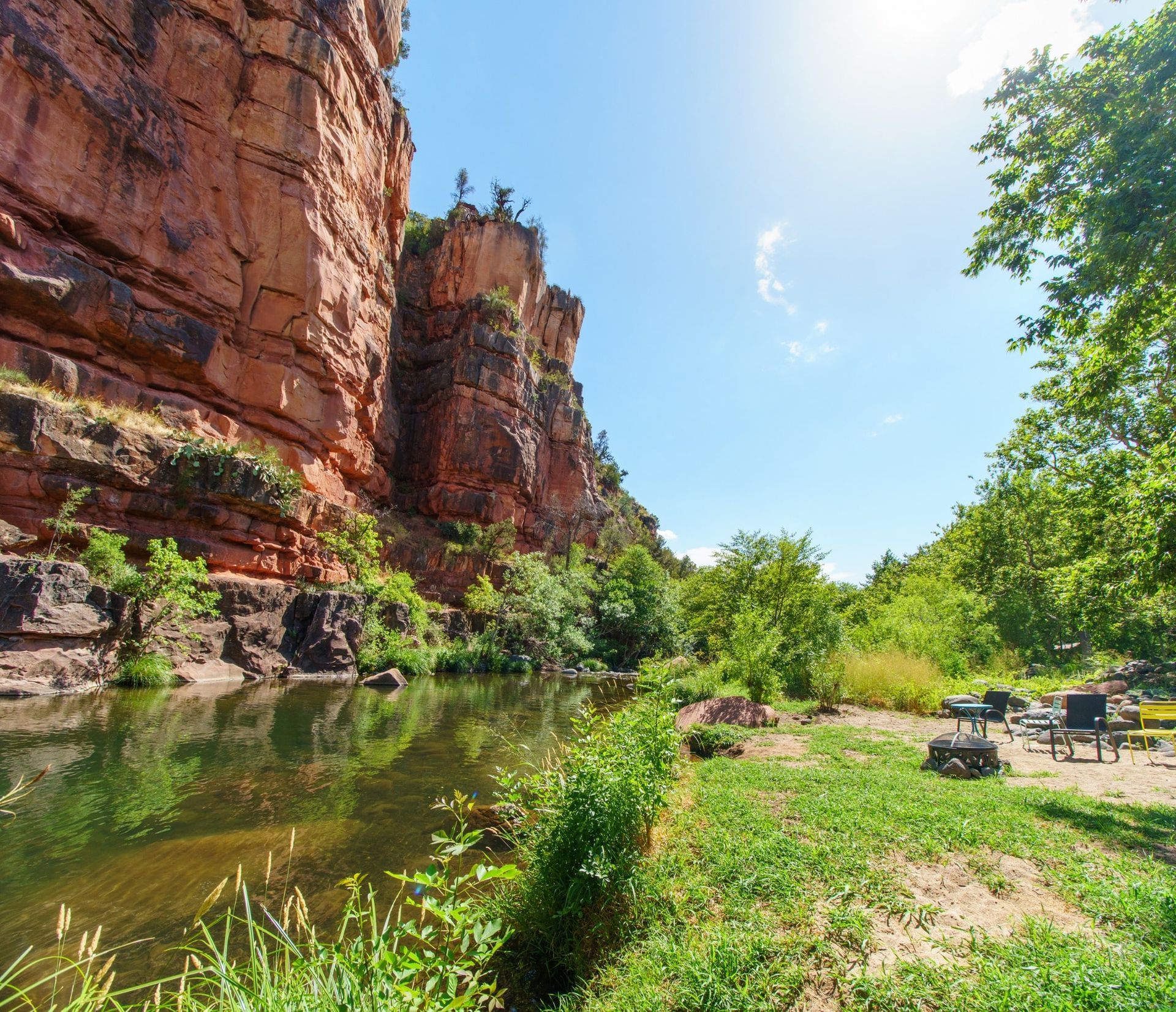 A river with a cliff in the background and a picnic table in the foreground.